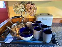 Overall view of kettle, toaster, mugs, bowls, tray, vase