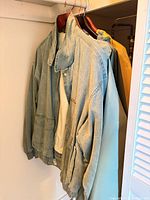 Four jackets hanging: light blue bomber, cream fleece, teal windbreaker, yellow raincoat
