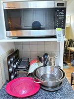 Overall view showing microwave, bakeware stack, colanders, stock pot