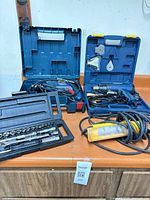 Overview of all tools: drill and heat tool in blue cases, work light, socket set