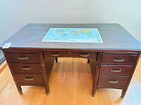 Front view of dark wood partner desk showing seven drawers, brass-tone pulls and wear on surface