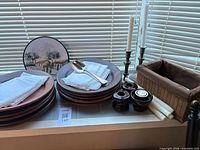 Overall lot view with plates, napkins, spoon, plaque, candlesticks, candles, basket