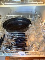 Roasting pan with base, flatware set in tray, and eight glass mugs on wire rack