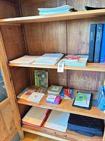 Overall view of shelves with binders, paper stacks, notebooks, stationery, carrying case