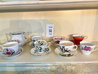 Front view of eight teacup and saucer sets with sugar bowl