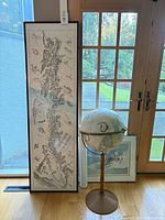 Globe on stand beside framed Alaska map and additional framed print