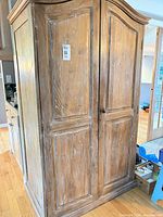 Front view of solid wood armoire wardrobe with distressed finish