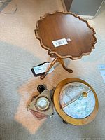 Overhead view of wooden tilt-top table, brass nautical compass on triangular base, floor globe with meridian ring, and small flush-mount compass.