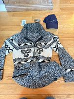 Cardigan laid flat with hat and belt buckle above