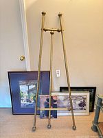 Full view of brass easel with artworks behind