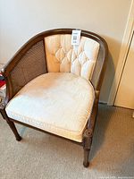 Front view of single cane-back upholstered club chair showing wood frame, cane panels and cream tufted seat
