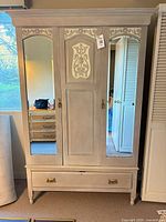 Front view showing mirrored doors, carved panel, lower drawer