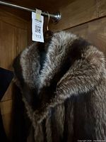 Front view of brown silver-tipped fur coat on hanger