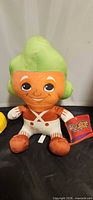Front view of Oompa Loompa plush with hat tag visible