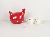 Group shot showing red polka-dot hen figurine and two white smile coin banks