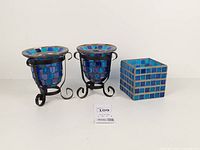 Full view of three blue mosaic glass candle holders: two urn-shaped in metal stands, one cube