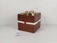 Full view of closed square teak ice bucket with rope accent and brass lid