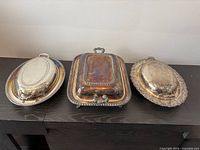 Three silver-plated covered dishes: two oval, one rectangular