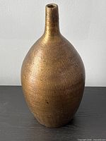 Front view of gold-tone bottle vase showing overall form and finish