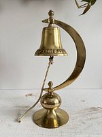Full view of brass captain's bell on stand showing overall design and rope
