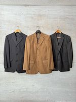 Three jackets hanging: charcoal pinstripe, camel tan, dark charcoal