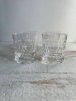 Four clear textured tumblers arranged on surface