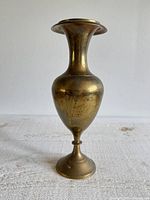 Front view of brass vase showing flared rim, bulbous body, pedestal foot