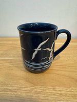 Full side view of dark blue mug with seagull and wave design