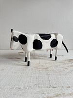 full left side view of spotted wooden cow figurine on tabletop