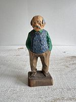 Front view of carved wood old man figurine on base