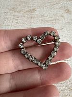 Full view of heart rhinestone brooch in hand