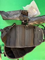 Black padded mesh arm sling and two rolled padded covers on green background