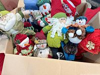 Box containing assorted plush Christmas snowmen, gnome and other decor