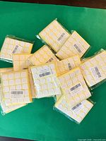 Multiple sealed packs of round white wick sticker sheets displayed on green background