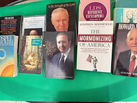 Front view of eight books and pamphlets laid out on green surface showing titles and formats