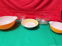 Front view of all five Pyrex bowls arranged on green cloth