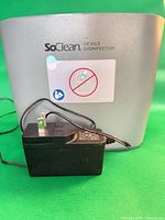 Front view showing SoClean branding, warning label, and power adapter