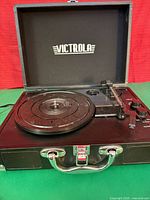 Turntable open showing platter, tonearm, controls and Victrola logo inside lid