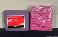 Front view of purple sheet set and rear of pink sheet set, both sealed