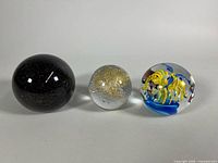 Three paperweights side by side showing relative sizes and colors