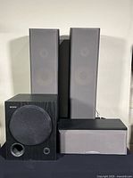 Group shot of two tower speakers, subwoofer, center speaker