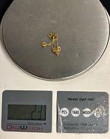 Earrings on digital scale displaying 2.3 g total weight
