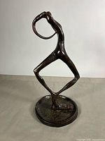 Front view of abstract cast metal figure on round base