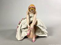Front view of ballerina figurine tying shoe