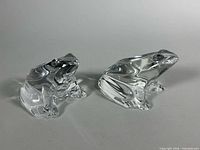 Front view of both clear crystal frog paperweights