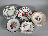Group shot of all china pieces: two individual plates, stack of six plates, two bird-motif bowls, candy dish partially visible