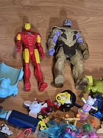 Iron Man, Thanos, blue hippo rocker and assorted small toys on wooden floor