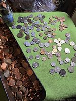 Metal tin filled with Canadian pennies beside spread of assorted world coins