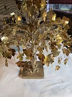 Front view of gold wire tree sculpture showing wire branches, metal leaves, and square base