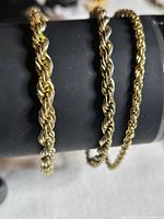 Three gold-tone rope bracelets on display cylinder showing chain thickness
